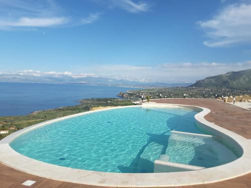 a large swimming pool next to a body of water at Hotel Antica Cascina Del Golfo in Scopello