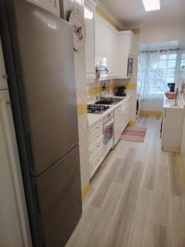 a kitchen with a stainless steel refrigerator and white cabinets at Lovely apartment in Cascais Park in Cascais