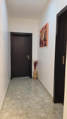 a hallway with a black door and a potted plant at stay at Creo's one bedroom swimming pool and gym in Ibeju