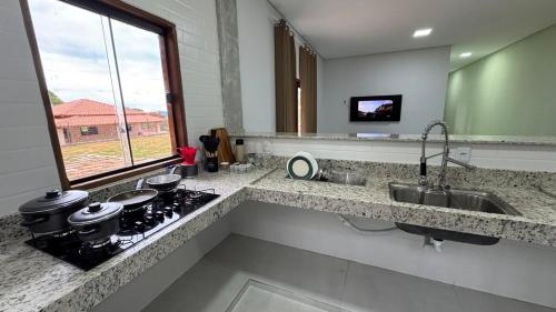 eine Küchentheke mit einer Spüle und einem Herd in der Unterkunft Hospedagem Café São Thomé in São Thomé das Letras