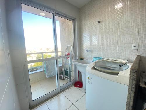 a bathroom with a toilet and a sink and a window at Movida Cabo Frio in Cabo Frio