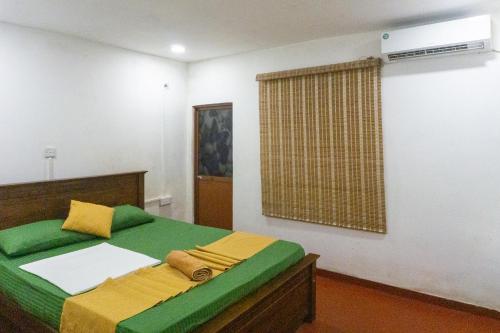 a bedroom with a bed with green and yellow pillows at Bambara Ella Agro Resort & Camping in Haputale