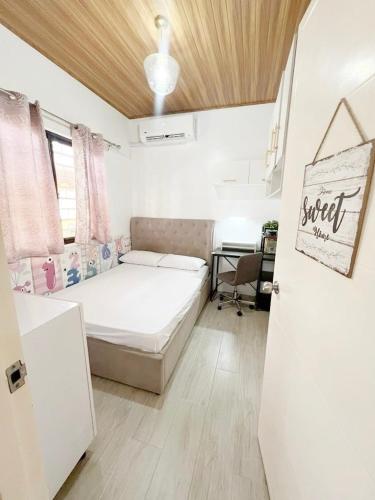 a small bedroom with a bed and a desk at Eco's Place GenTri - Family Bungalow in General Trias