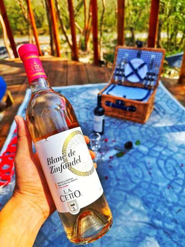 una persona che tiene una bottiglia di vino su un tavolo di Glamping El Cielo Adventures a Gómez Farías