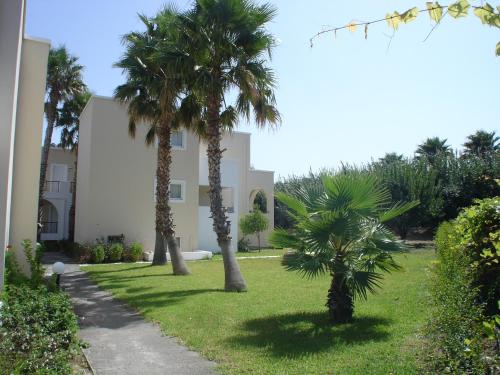 two palm trees in a yard next to a building at Andromeda Hotel Apartments in Kos Town