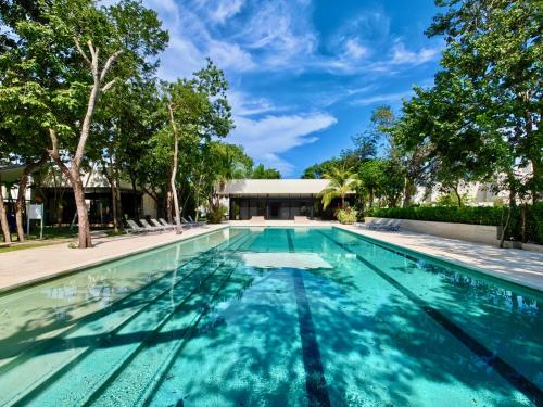 a swimming pool with blue water and trees at Palmara 13 by Bookking Guys in Playa del Carmen