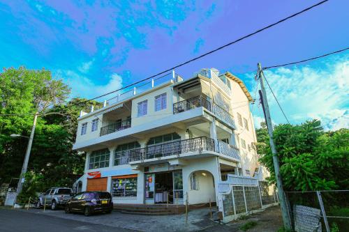 a white building with cars parked in front of it at Logement cosy proche plage in Grand Gaube