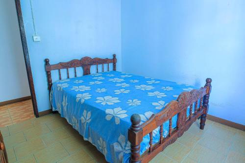 a blue bedroom with a wooden bed with a blue blanket at Logement cosy proche plage in Grand Gaube