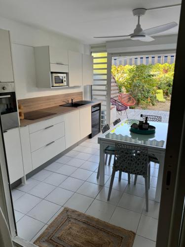 a kitchen with white cabinets and a table in it at Ti paradis créole - Sainte-Anne in Plaisance
