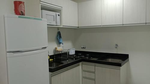 a kitchen with white cabinets and a white refrigerator at Studio 412 in Marília