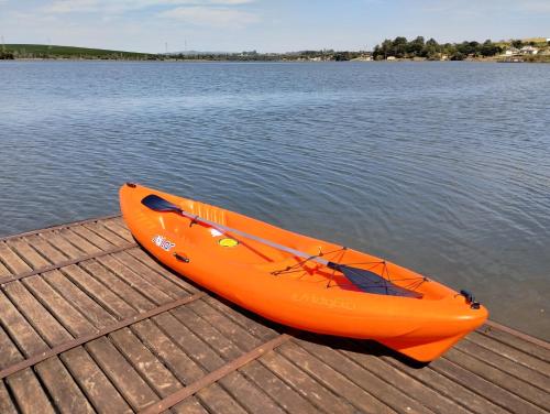 an orange kayak sitting on a dock next to the water at Casa de Charme Camargos in São João del Rei
