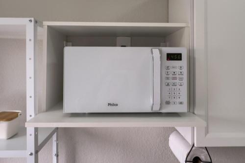 a microwave oven on a shelf in a kitchen at Ap Expo SP e Zoológico in Sao Paulo