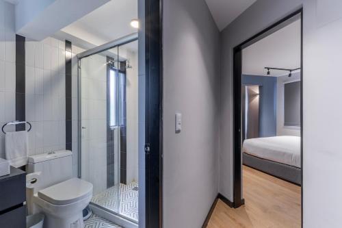 a bathroom with a toilet and a shower and a bed at Capitalia Condesa Escandon in Mexico City