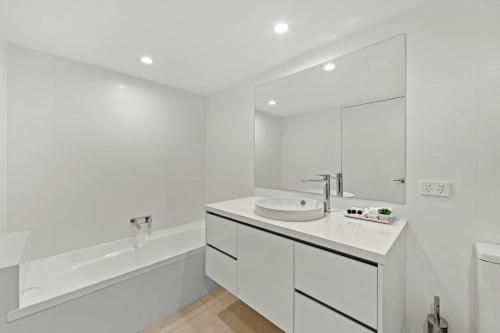 a white bathroom with a sink and a tub at Picture Point Terraces in Noosa Heads
