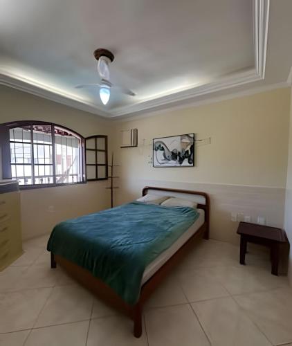 a bedroom with a bed with a green comforter at Casa Entre o Mar e a Lagoa in Saquarema