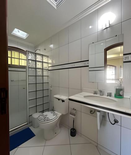 a white bathroom with a toilet and a sink at Casa Entre o Mar e a Lagoa in Saquarema