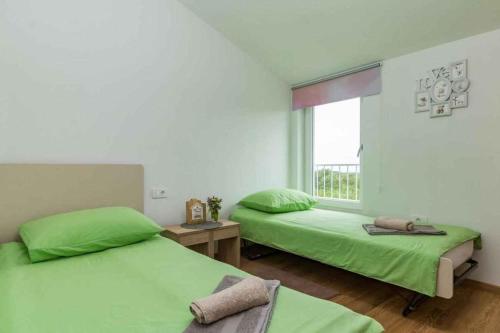 two green beds in a room with a window at Holiday home in Jakovici - Istrien 53392 in Bašići