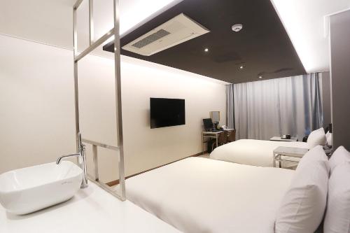 a bedroom with two beds and a sink and a mirror at Louis Hotel in Gangneung