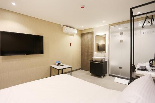 a hotel room with a bed and a bathroom at Louis Hotel in Gangneung