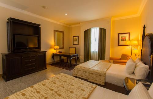 a hotel room with two beds and a flat screen tv at Quinta Edén Villahermosa in Villahermosa