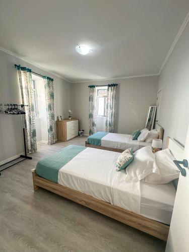 ein Schlafzimmer mit zwei Betten und zwei Fenstern in der Unterkunft Maré Alta - Deluxe Stay Minutes To Marina Center in Vila Franca do Campo