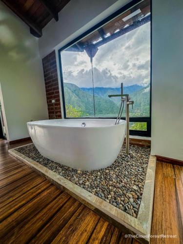 a bath tub in a room with a large window at The Cloud Forest Retreat in Pelagallo