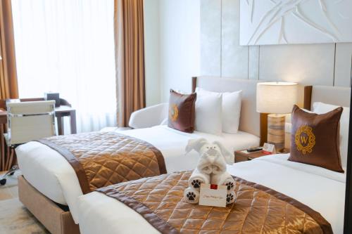 a hotel room with two beds with a dog on the bed at Grand Westside Manila Bay in Manila
