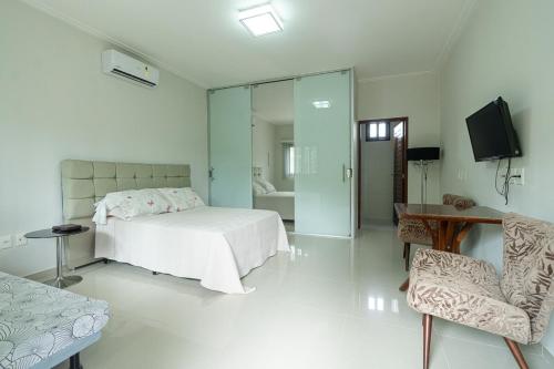 a bedroom with a bed and a tv and a chair at Casa Rio Doce in Natal