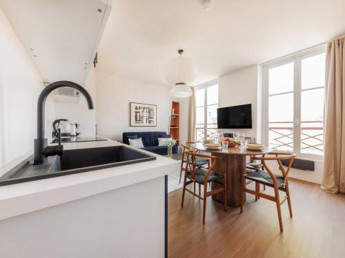 une cuisine avec un évier et une table avec des chaises dans l'établissement Cosy Apartment Le Bon Marche, à Paris