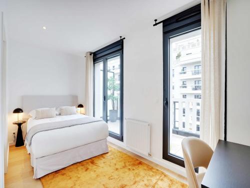 une chambre avec un lit blanc et une grande fenêtre dans l'établissement Duplex with terrace in Levallois, à Levallois-Perret