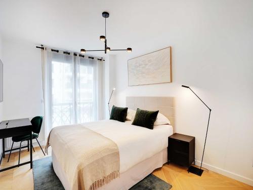 une chambre blanche avec un lit et un bureau dans l'établissement Sleek & Refined Apartment - Levallois-Perret, à Levallois-Perret