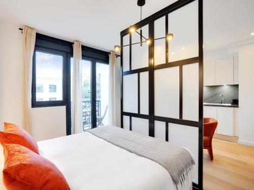 Cet appartement comprend une chambre avec un lit blanc et une cuisine. dans l'établissement Studio Sleek & Refined - Levallois-Perret, à Levallois-Perret