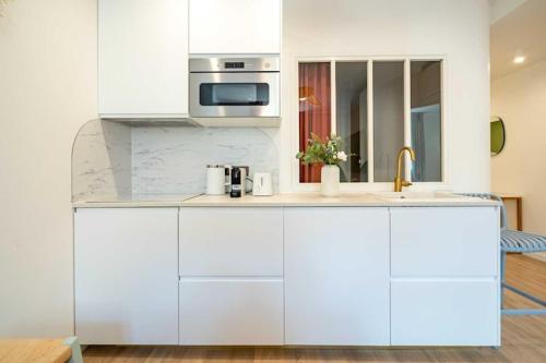 une cuisine blanche avec un évier et un micro-ondes dans l'établissement Beautiful 2bdr flat - Hyper centre St Tropez, à Saint-Tropez