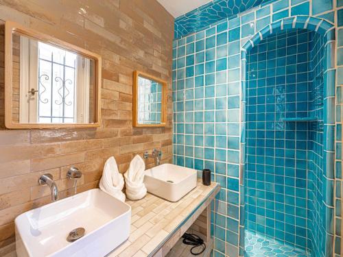 La salle de bains est pourvue de carrelage bleu, d'un lavabo et d'un miroir. dans l'établissement Sublime Appt - 2BD 4P - Terrace sea view - Antibes, à Antibes