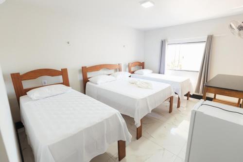 a room with two beds and a window at Hotel Sanches in São Mateus