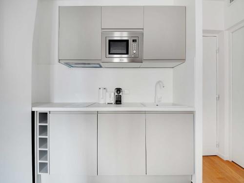 - une cuisine blanche avec un four micro-ondes au-dessus d'un évier dans l'établissement Peaceful Apartment - 1BR 4P - Sacré Coeur, à Paris