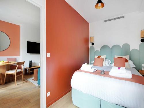 une chambre avec un lit avec un mur orange dans l'établissement Peaceful Apartment - 1BR 4P - Sacré Coeur, à Paris