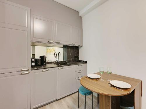 une cuisine avec des armoires blanches et une table en bois dans l'établissement Cosy apartment with balcony - 2BR 6P- La Roquette, à Paris