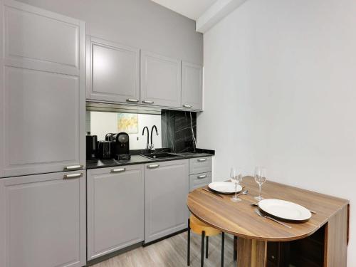 une cuisine avec une table en bois et des armoires blanches dans l'établissement Modern apartment & terrace - 2BR 6P - Near Nation, à Paris