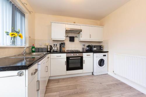 a kitchen with white cabinets and a washer and dryer at Durham 3Bedroom Home Away From Home in Durham