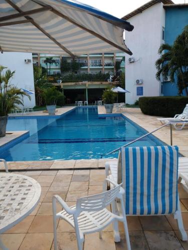 a swimming pool with a pair of chairs and a table and a swimming pool at Condomínio Arituba Tropical - Praia Camurupim - Apartamento a 150m da praia in Nísia Floresta