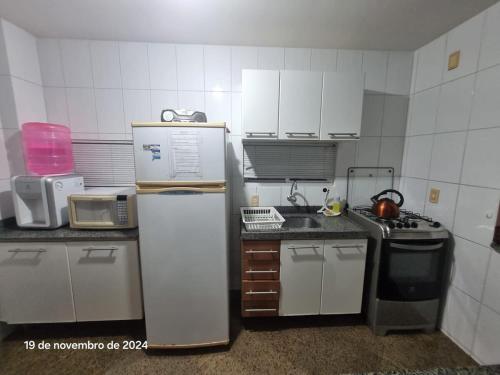 a small kitchen with a refrigerator and a stove at Condomínio Arituba Tropical - Praia Camurupim - Apartamento a 150m da praia in Nísia Floresta
