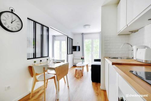 une cuisine avec une table et une horloge au mur dans l'établissement Cozy apartment - 1BR 4P Montmartre Sacré C ur, à Paris