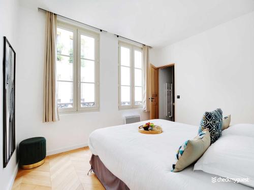 Cette chambre blanche dispose de 2 lits et de 2 fenêtres. dans l'établissement Charming apartment- 2BR 6P - Le Marais, à Paris
