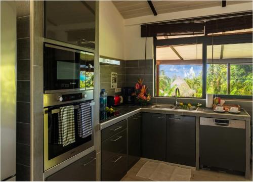 una cucina con mobili neri e una grande finestra di FARE ARIITEA a Bora Bora