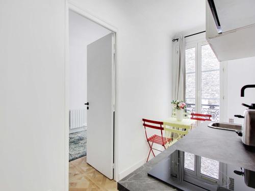 - une cuisine avec des murs blancs et une table avec des chaises rouges dans l'établissement Cozy Studio - 4P - Place de la Bastille, à Paris