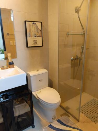 a bathroom with a toilet and a sink and a shower at Saint Honore Executive: 6 guests, 5 beds, 2 bedrooms, 2 bathrms in Iloilo City