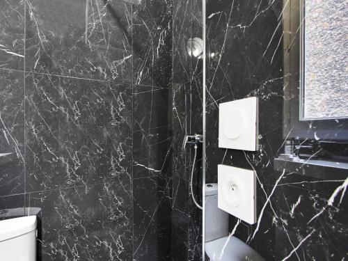 La salle de bains en marbre noir est pourvue de toilettes et d'une douche. dans l'établissement Cozy Studio - 4P - Place de la Bastille, à Paris