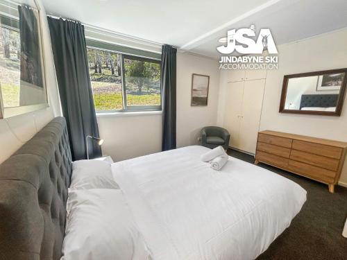a bedroom with a white bed and a window at Frogmouth Hutte in Crackenback