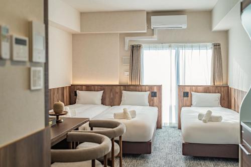 a hotel room with two beds and a desk at Apartment Hotel 11 Kuromon 4 in Osaka
